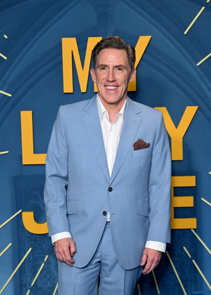 a man in a light blue suit stands in front of a sign that says my life