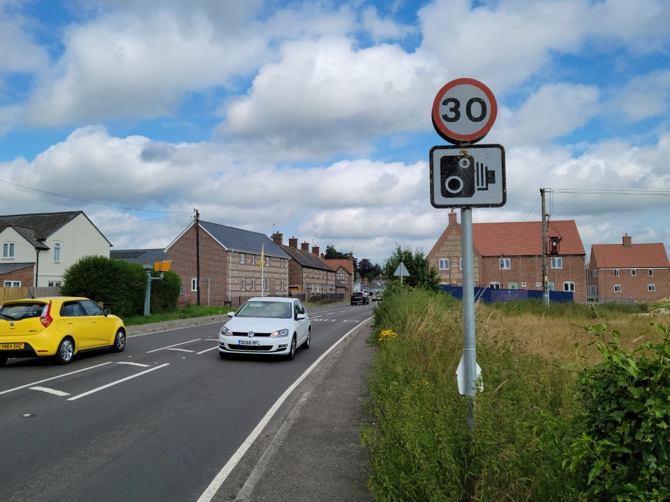 a white car is driving past a sign that says 30