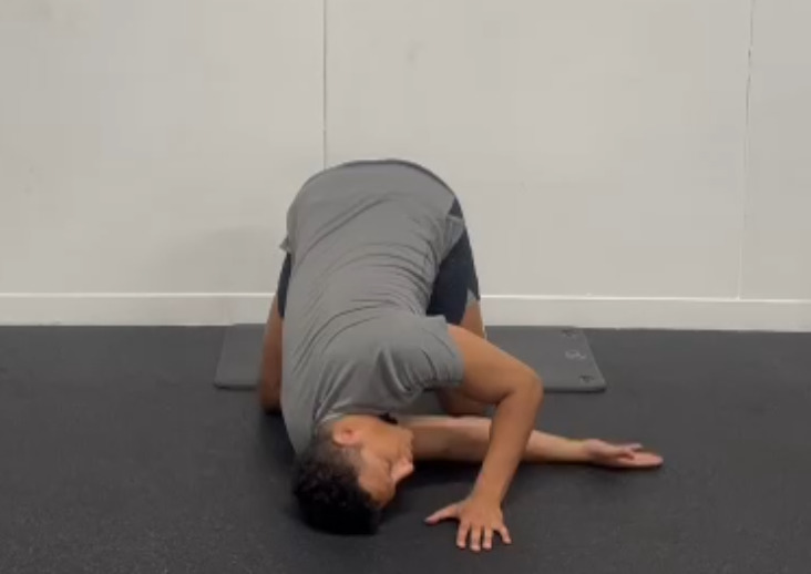 a man is doing a yoga pose on a mat in a gym .