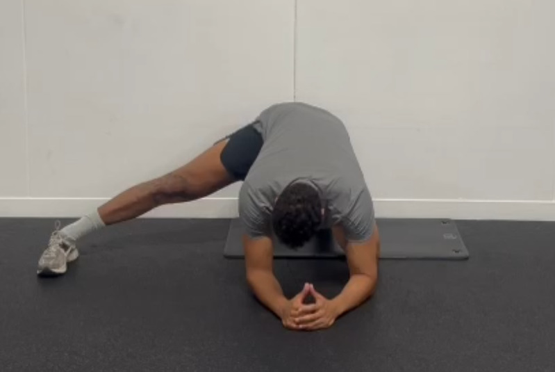 a man is stretching his legs on a mat in a gym .
