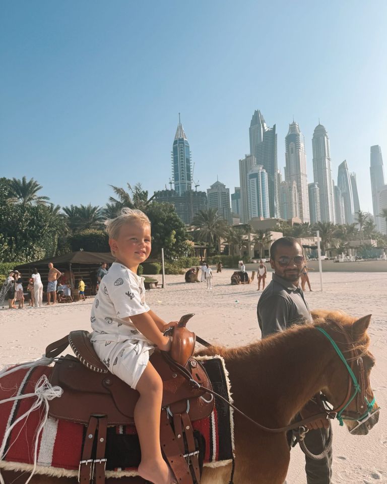 a little boy is riding a horse on the beach