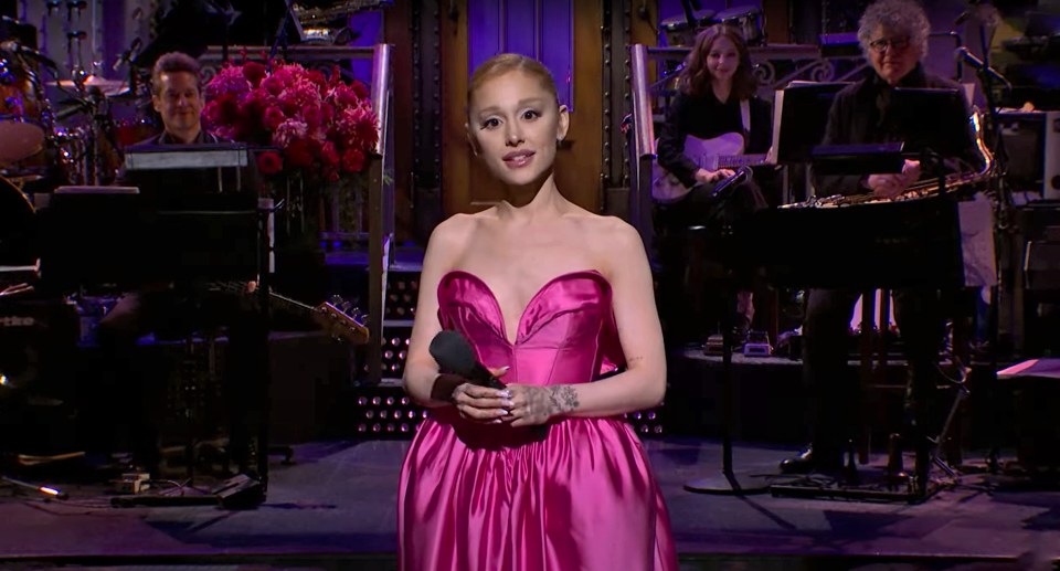 a woman in a pink dress is singing into a microphone