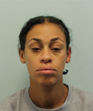 a woman in a grey shirt looks at the camera