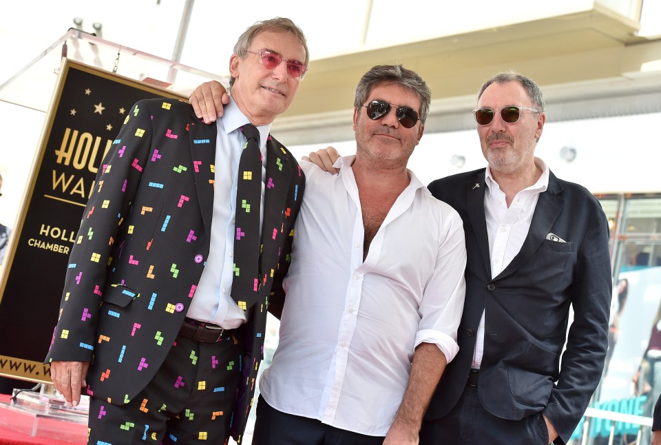 three men stand in front of a sign that says hollywood chamber