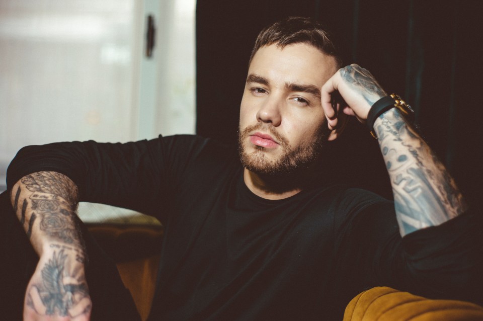 a man with tattoos on his arms looks at the camera