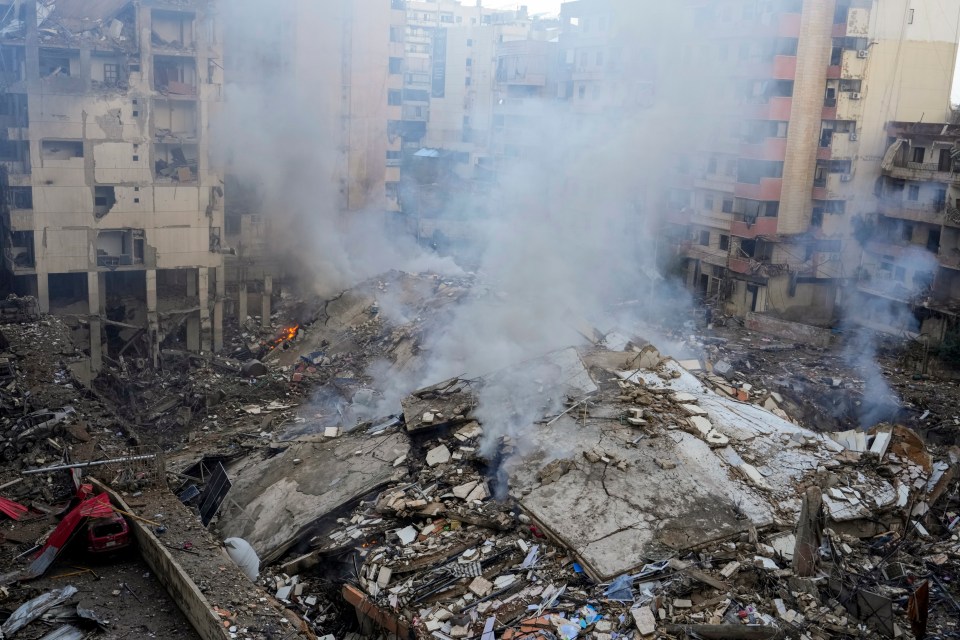a pile of rubble with smoke coming out of it and a building that says ' a ' on it