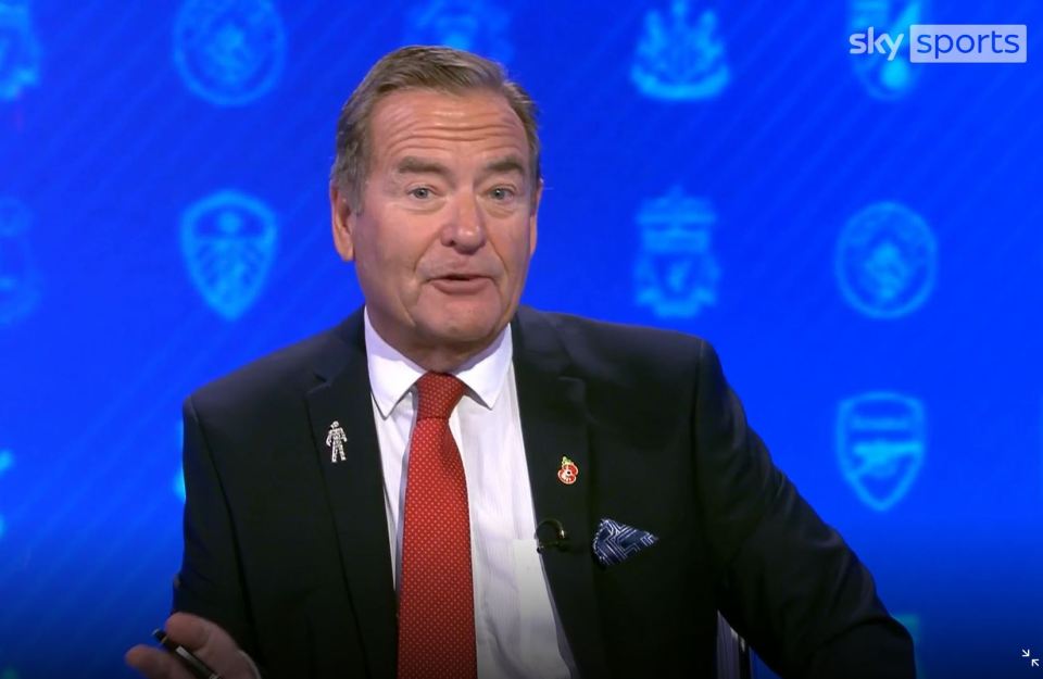 a man in a suit and tie is talking in front of a blue background that says sky sports
