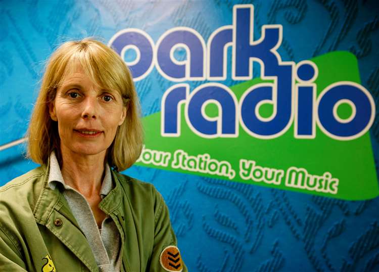 a woman stands in front of a sign for park radio