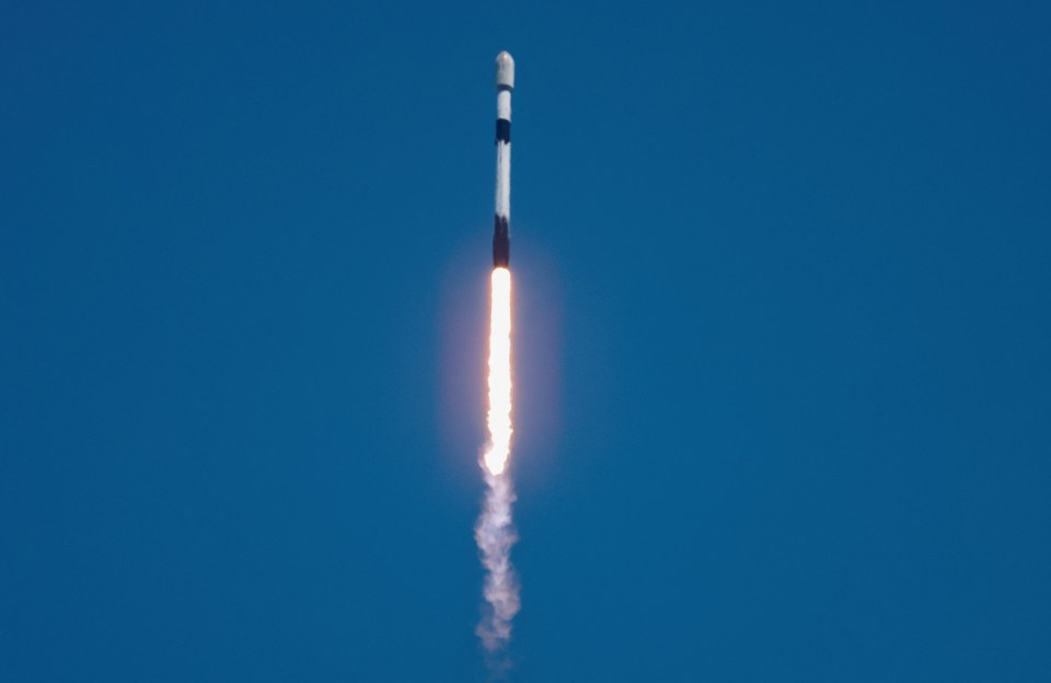 a rocket is flying through a clear blue sky