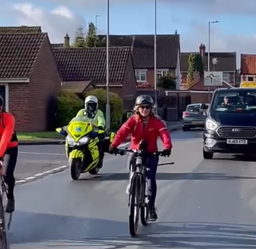 a group of people are riding bikes down a street next to a motorcycle .