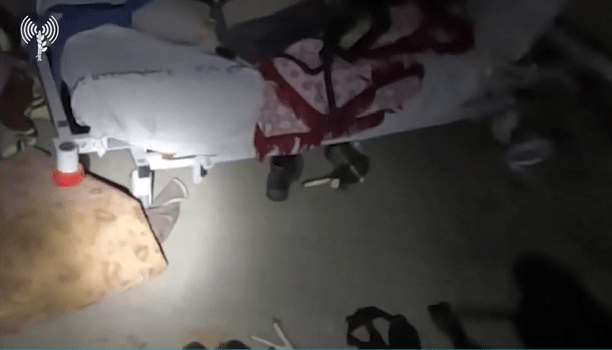 a person laying in a hospital bed with a flashlight on the floor