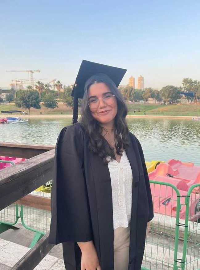 a woman in a graduation cap and gown is standing in front of a lake .