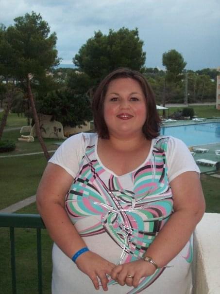 a woman in a colorful shirt is standing next to a pool .