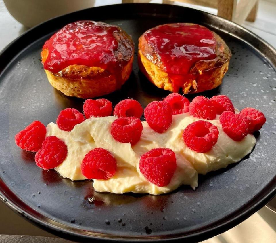 a black plate topped with raspberries and whipped cream