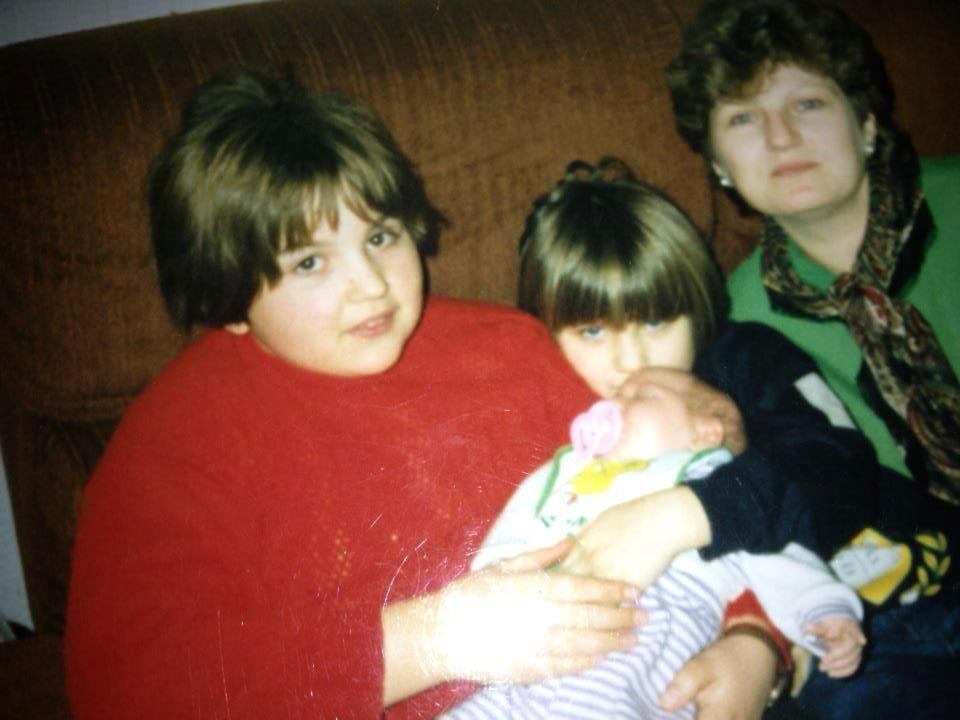 a woman in a red sweater is holding a baby