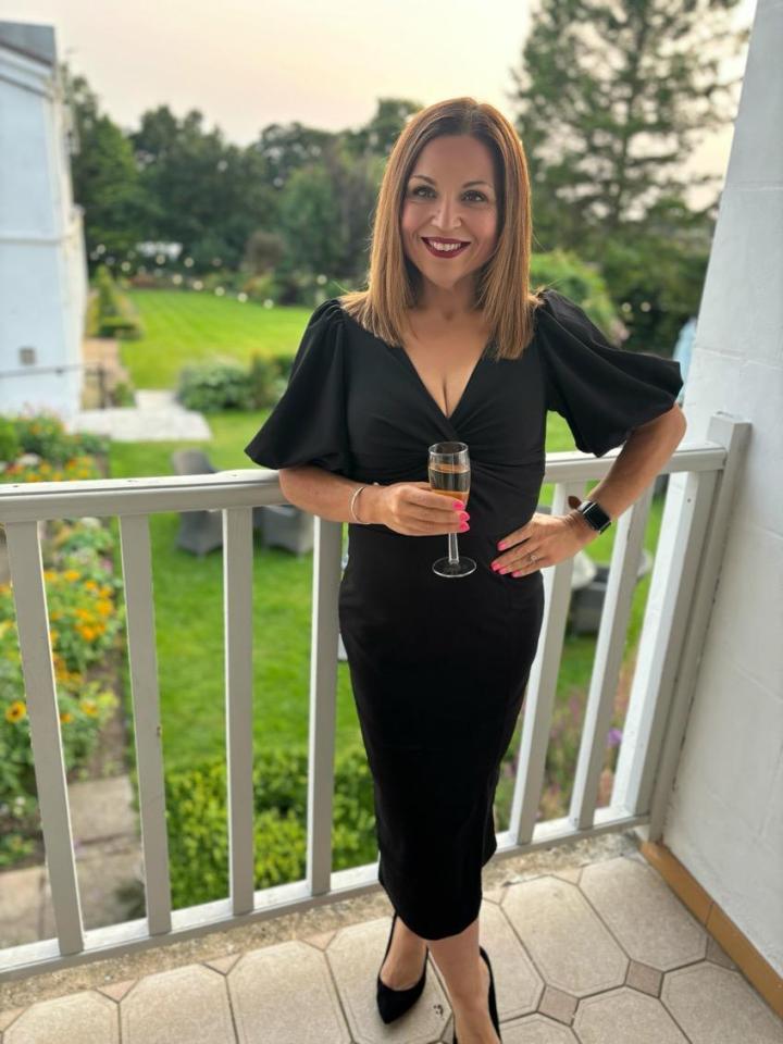 a woman in a black dress is holding a glass of champagne
