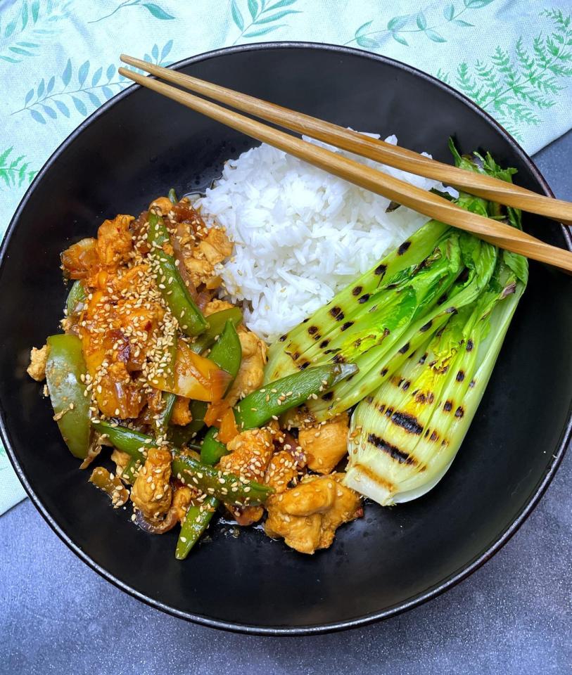 a bowl of food with chopsticks and rice and vegetables