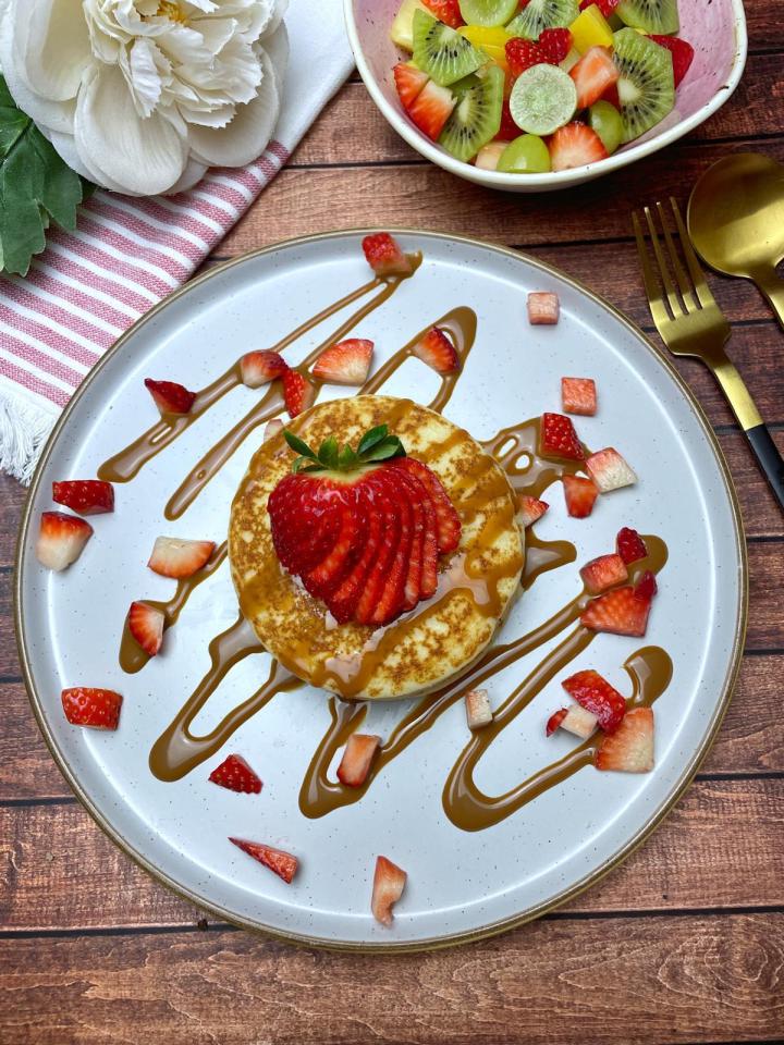 a pancake with strawberries and caramel sauce on a plate
