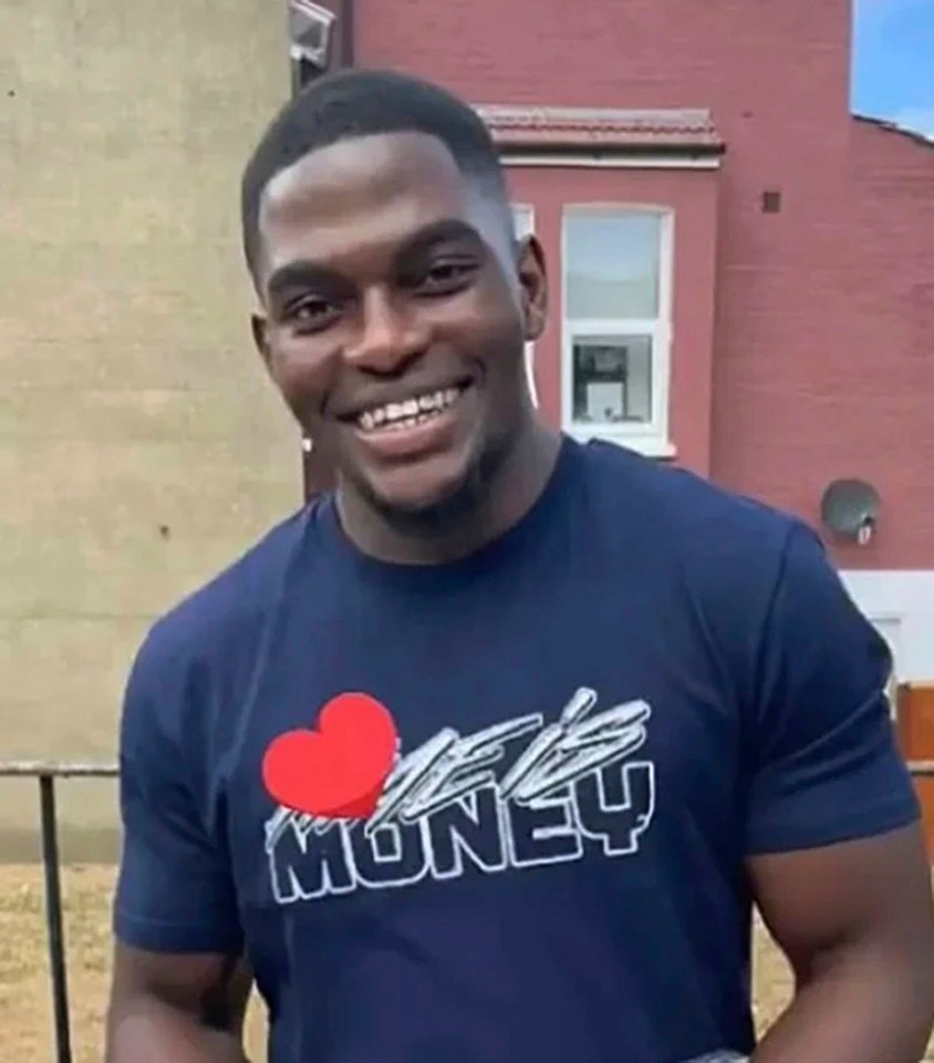 a man wearing a t-shirt that says love money is smiling in front of a red building .