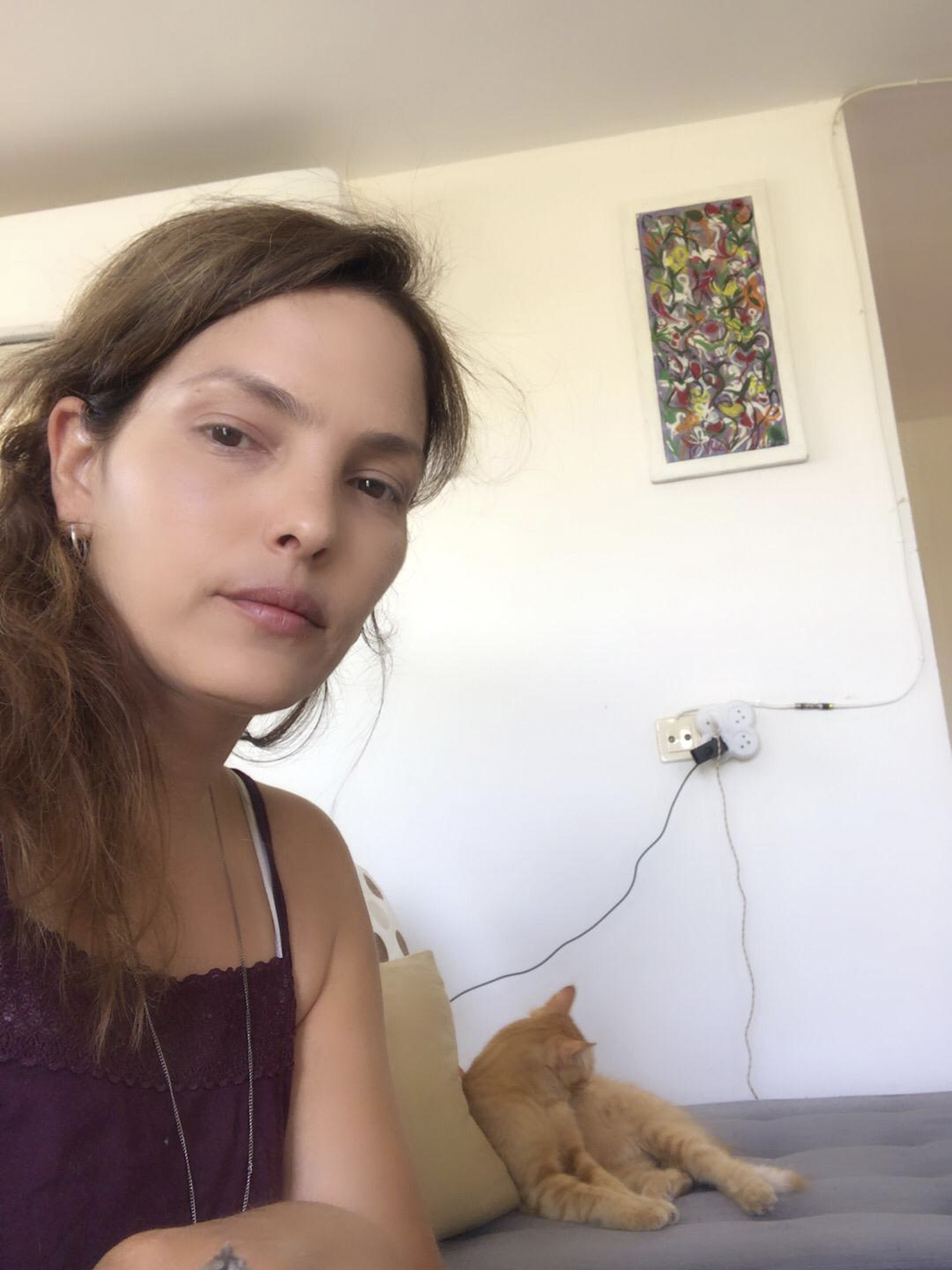 a woman sits on a couch next to an orange cat