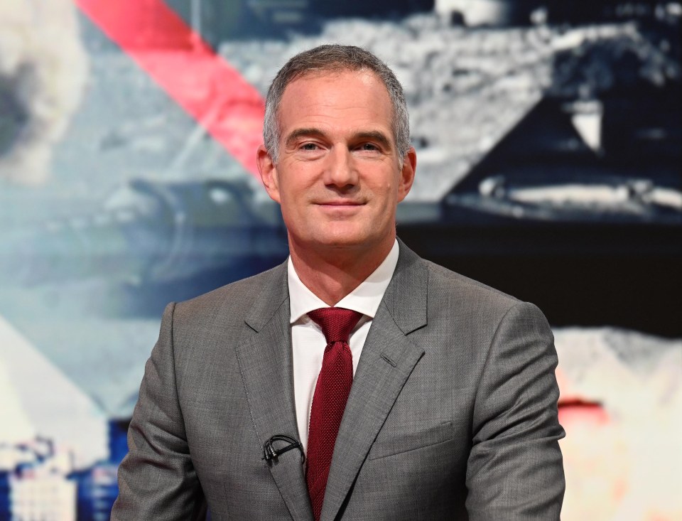 a man in a suit and tie stands in front of a screen