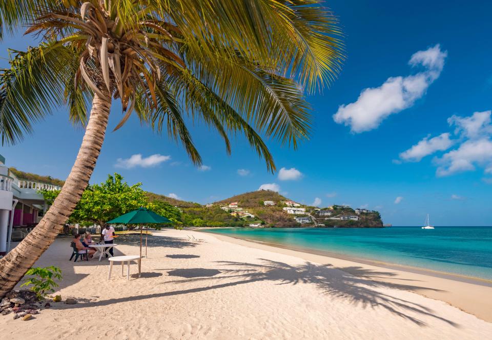 a group of people sit at a table on a tropical beach