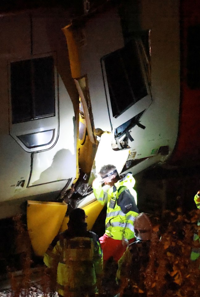 a group of people are standing in front of a train that has been damaged