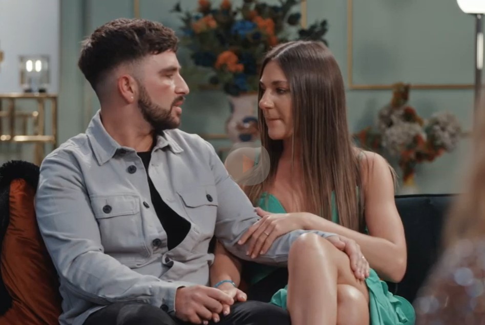 a man and woman sit on a couch looking at each other