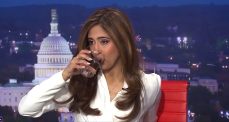 a woman drinking a glass of water in front of the capitol building