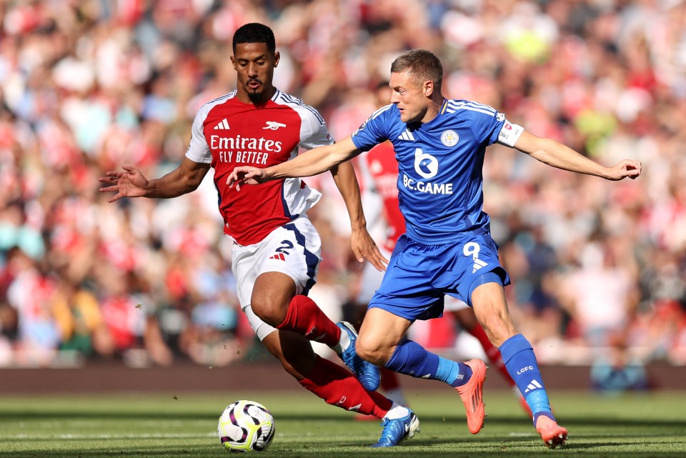 two soccer players one in a red emirates fly better jersey and one in a blue fc game jersey