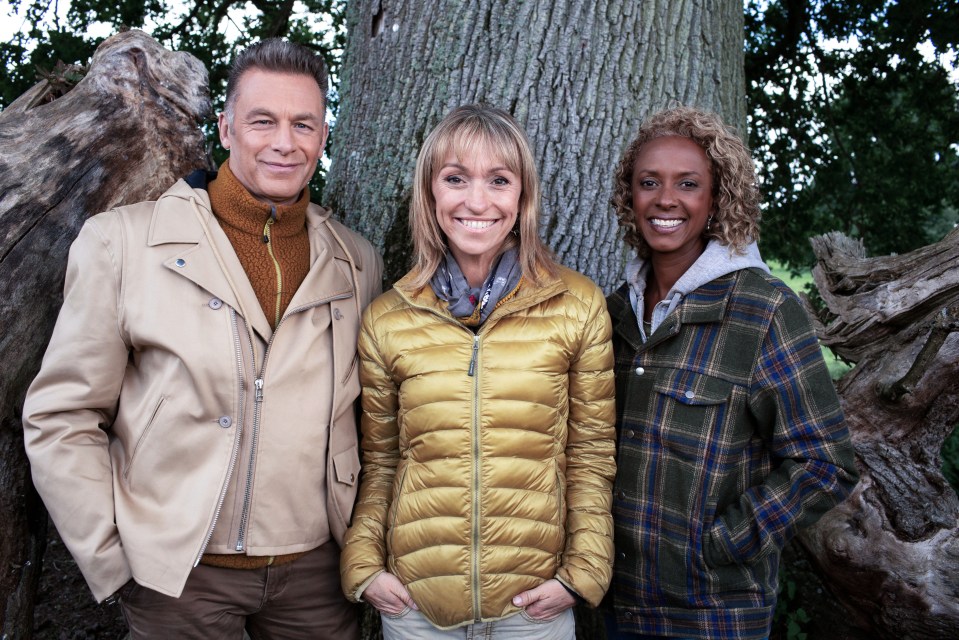 three people standing next to each other in front of a tree