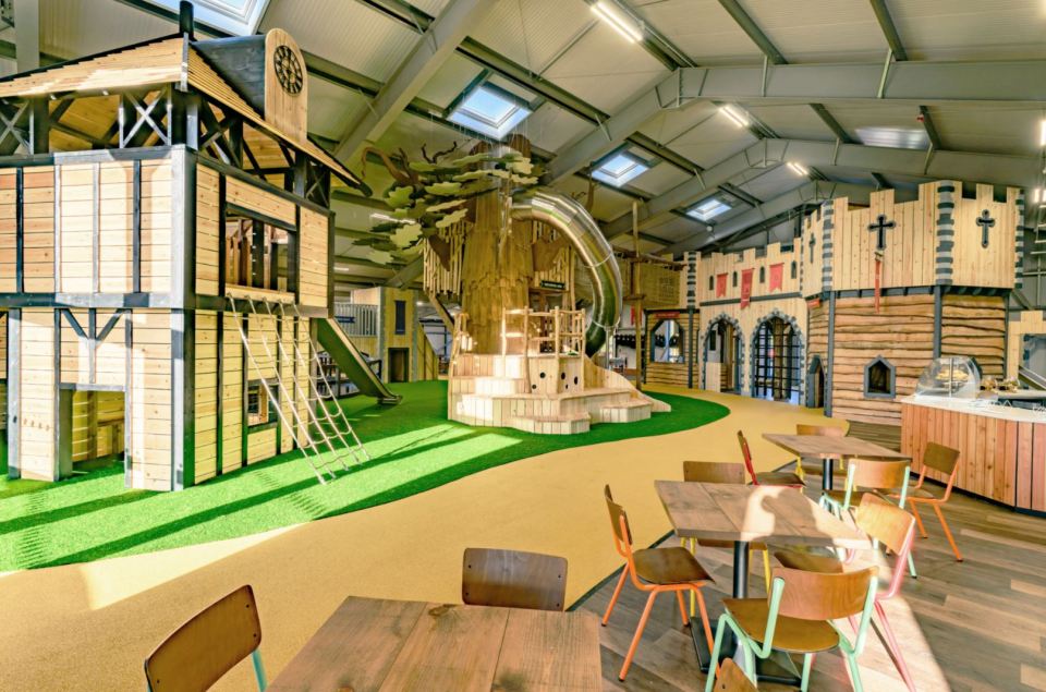 a large wooden play area with tables and chairs
