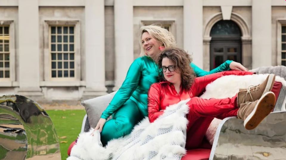 two women sitting on a couch in front of a building