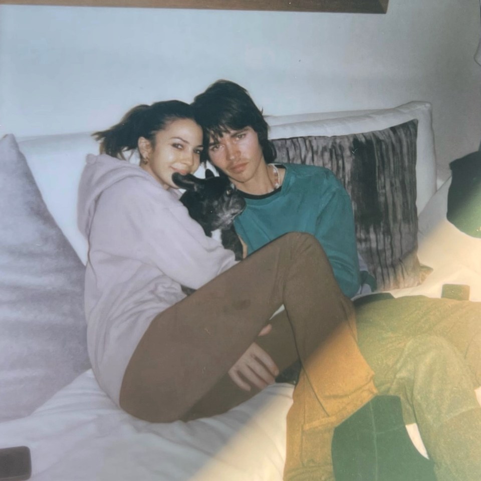 a man and a woman sitting on a bed with a dog