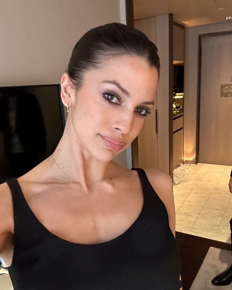 a woman in a black tank top is taking a selfie