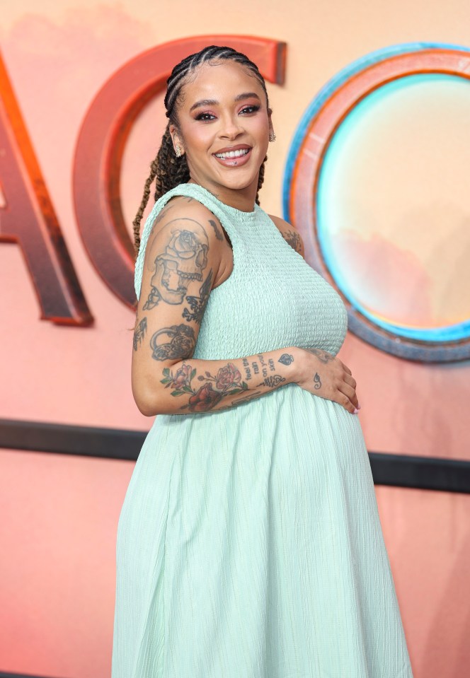 a pregnant woman with tattoos on her arm is smiling