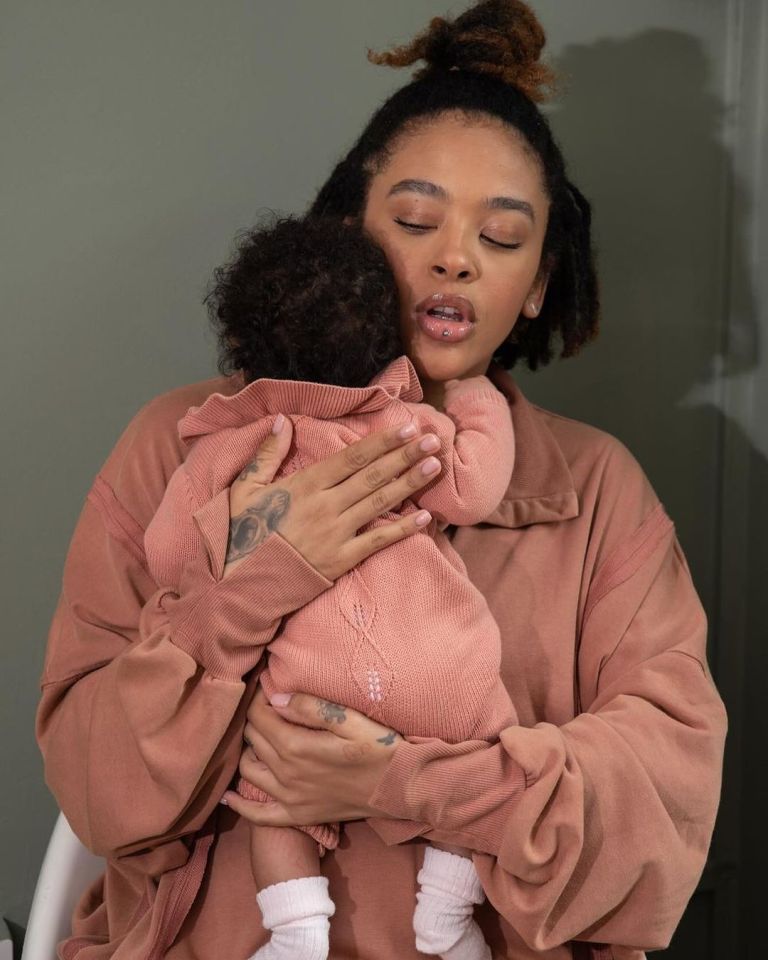 a woman in a brown sweater is holding a baby
