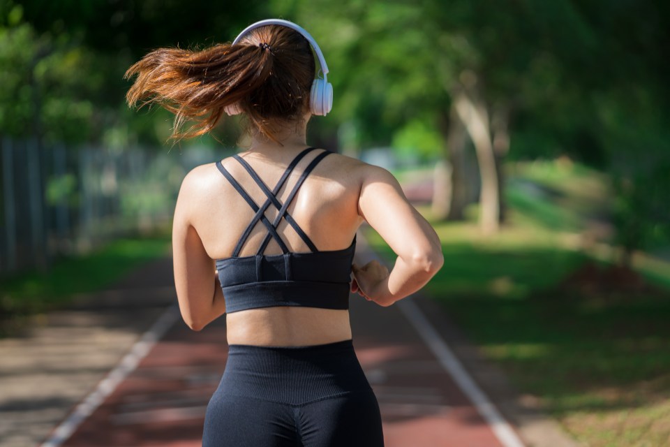 a woman wearing headphones is running on a track