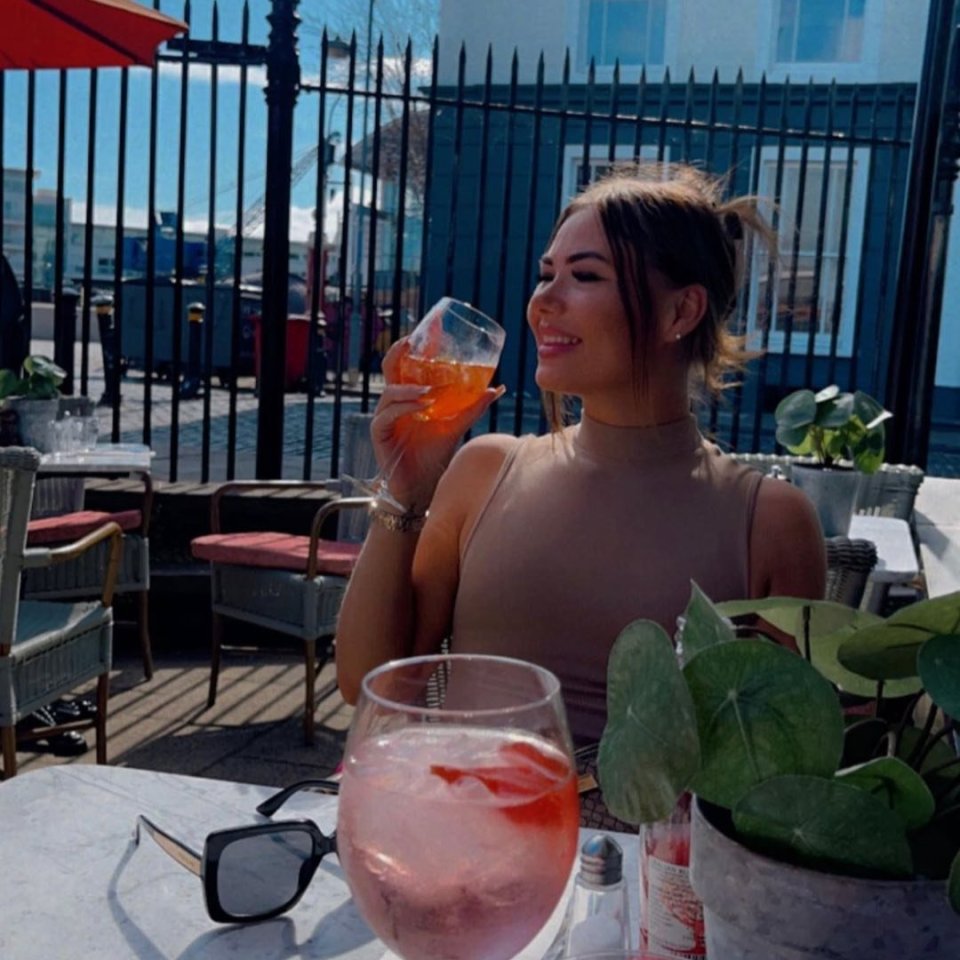 a woman sitting at a table with a drink in her hand