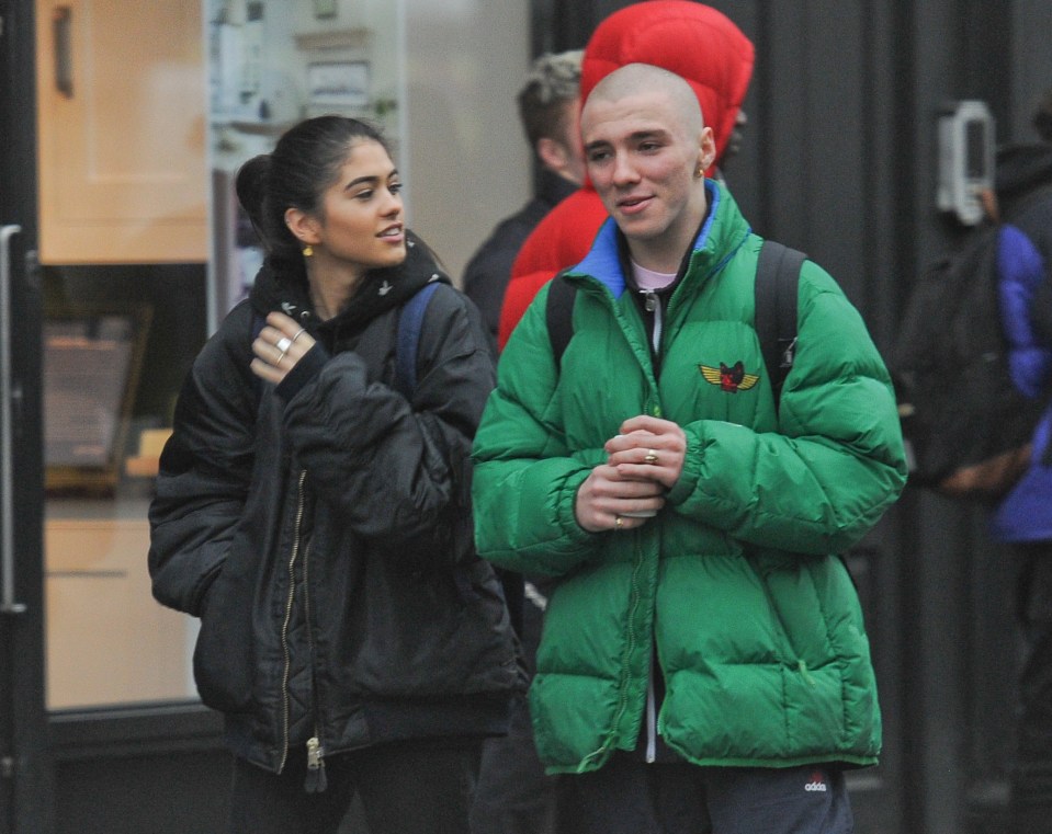a man in a green adidas jacket stands next to a woman in a black jacket