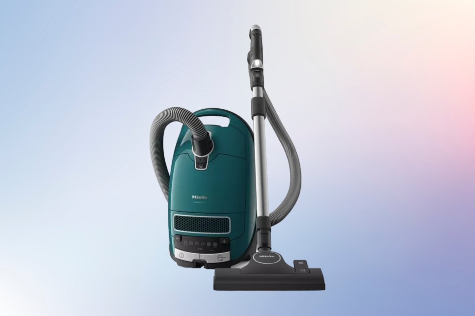 a green miele vacuum cleaner against a blue background