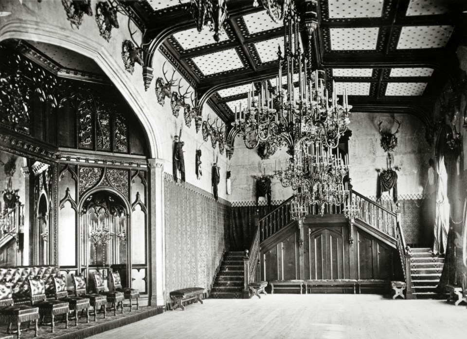 a black and white photo of a large room with stairs and a chandelier