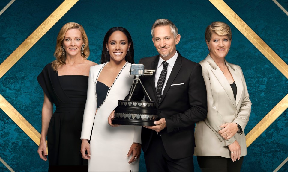 a man in a suit holds a trophy in front of three women