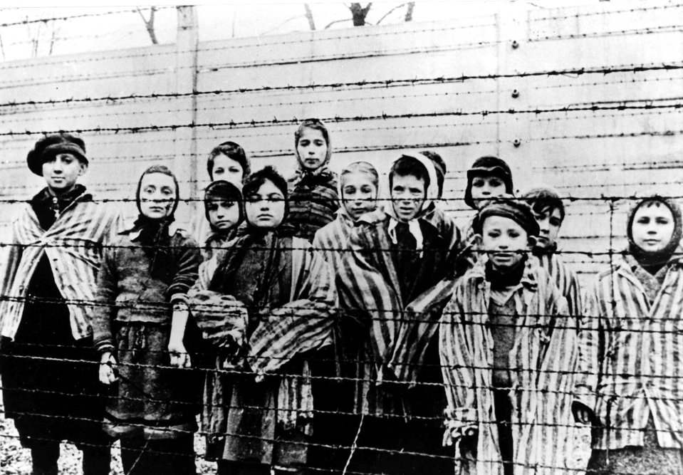 a group of people standing behind a barbed wire fence