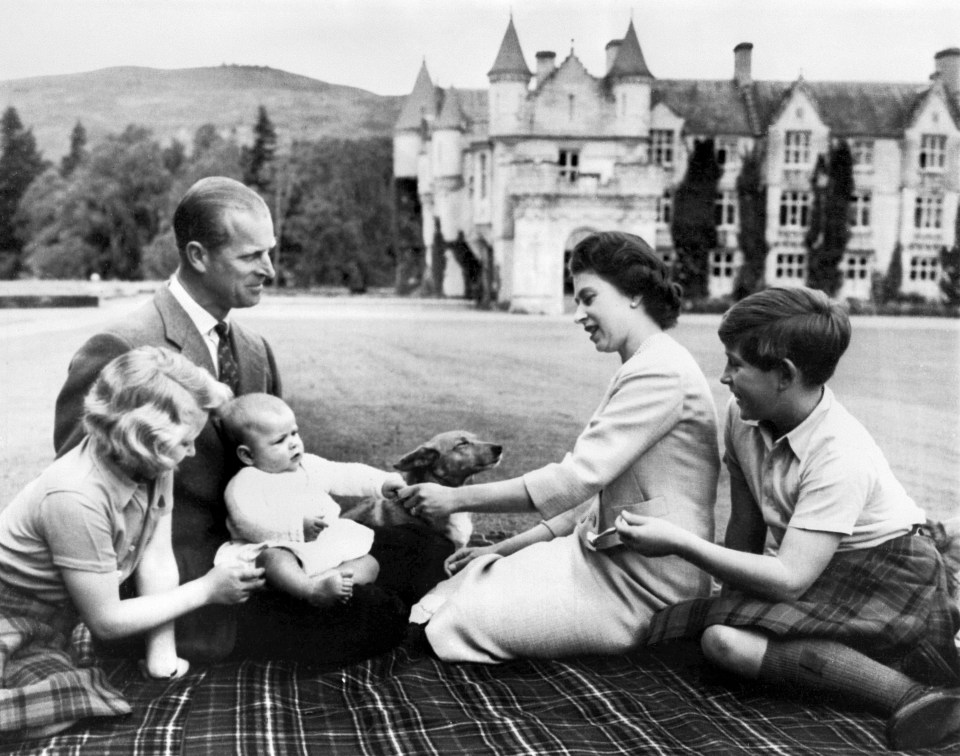 a black and white photo of a family having a picnic in front of a castle
