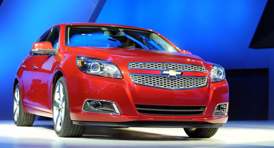 a red chevrolet malibu is on display at a car show