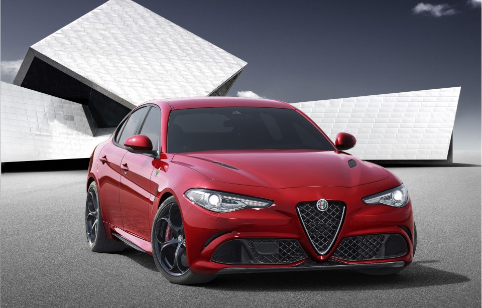 a red alfa romeo is parked in front of a white building