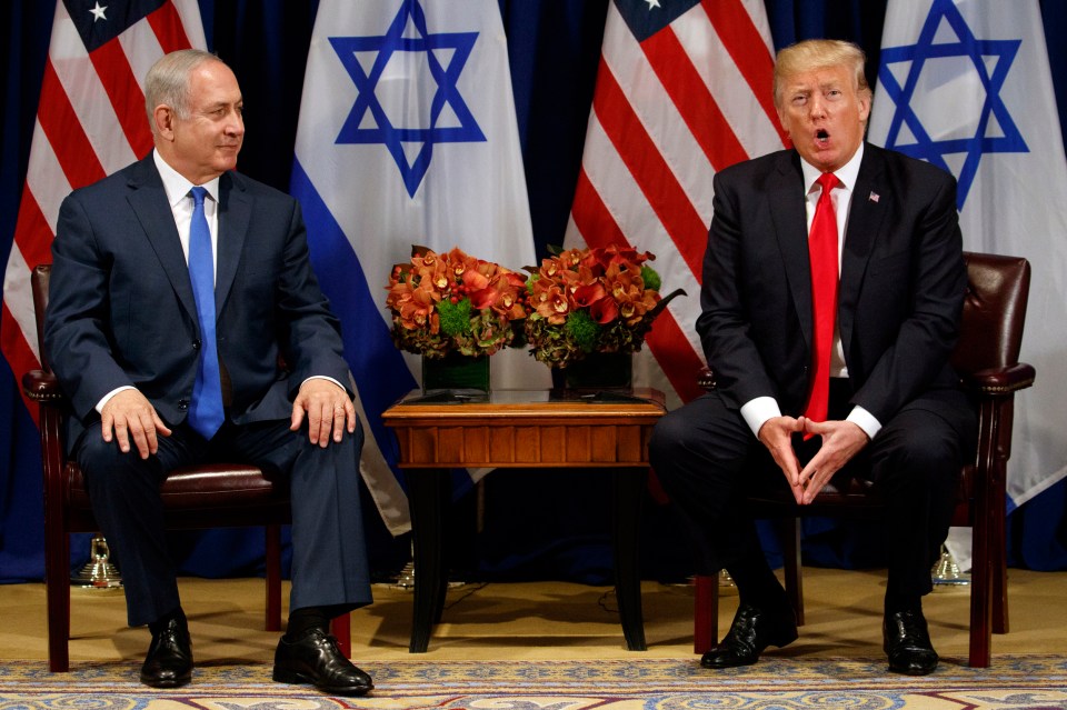 two men in suits and ties are sitting in front of flags