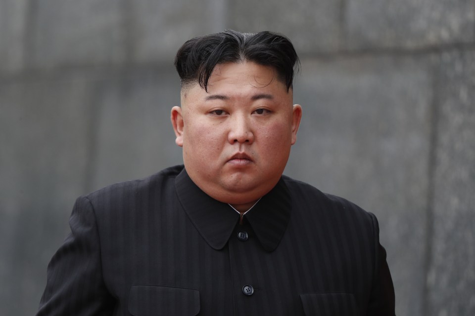 a man with a shaved head is wearing a black suit