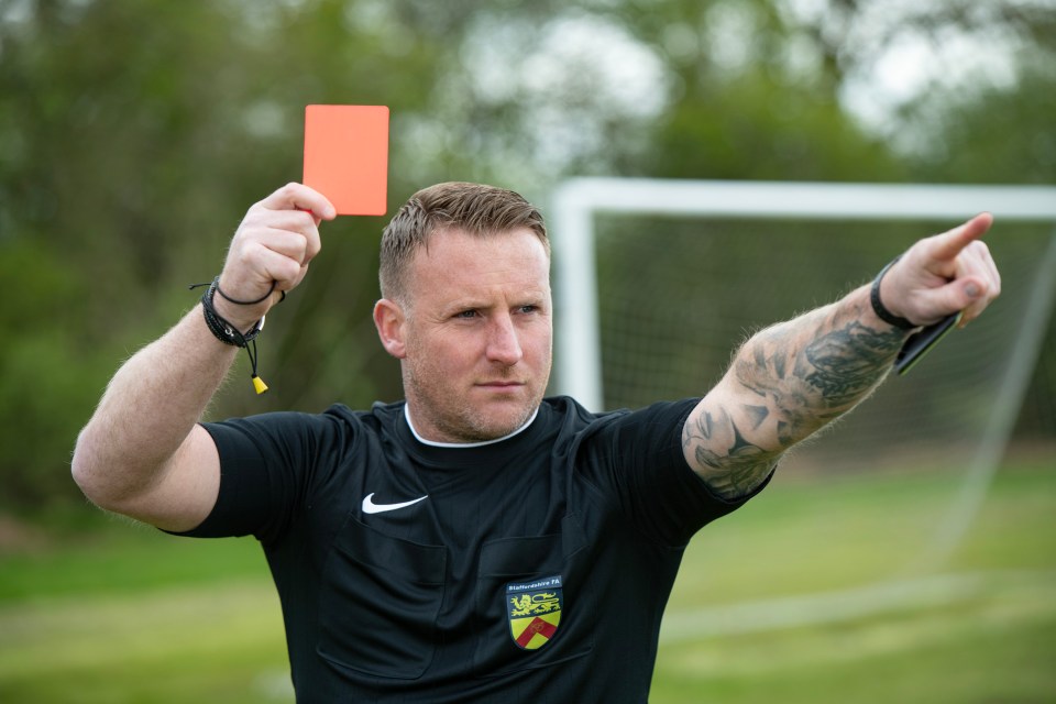 a man in a black nike shirt holds up a red card
